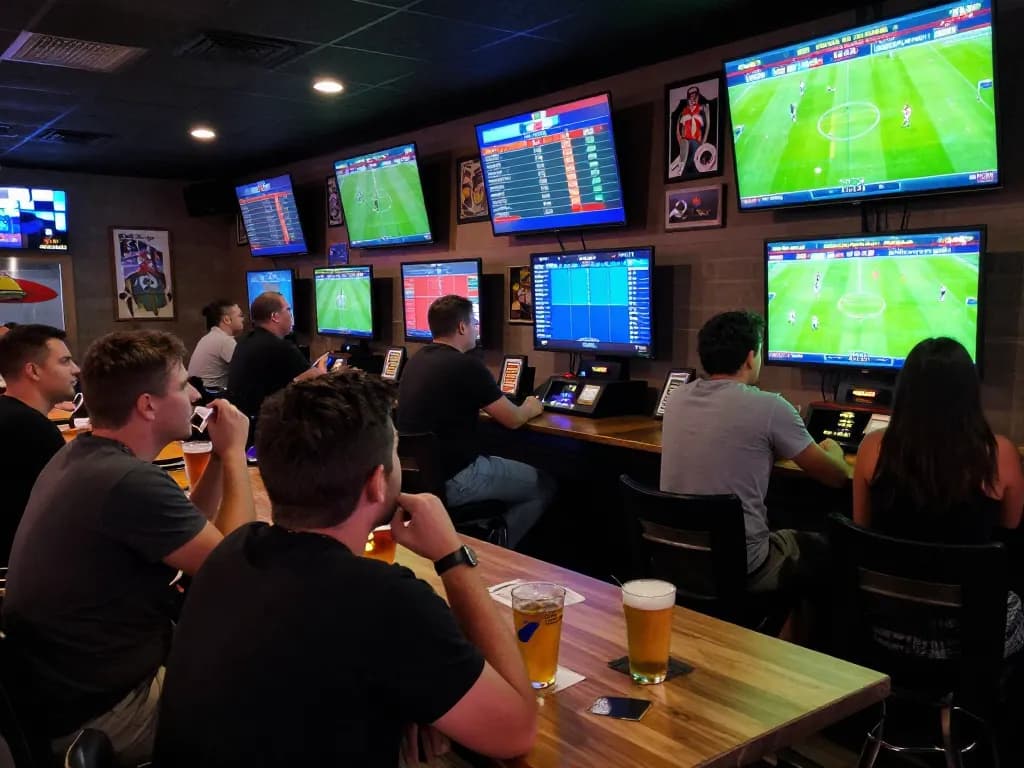 Kết quả bóng đá displayed on multiple screens as patrons enjoy sports betting excitement at a lively bar